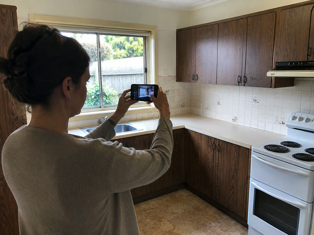 A customer photographing an old kitchen on her phone before booking a clearance